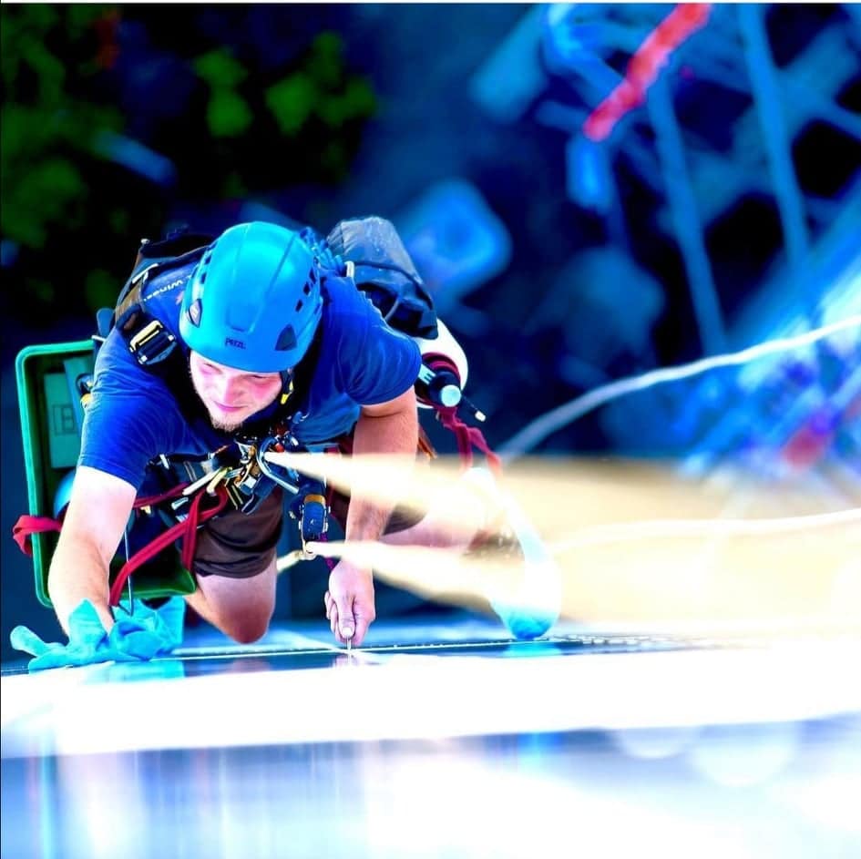 Ein Industriereiniger seilt sich sicher an einer Fassade ab